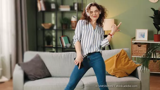 Junge Frau tanzt mit Kopfhörern in Ihrem Wohnzimmer Mit dem Jugenbonus der Bausparkassen werden junge Menschen unterstützt. (Foto: © VAKSMANV / stock.adobe.com)